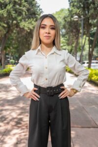 Home A confident woman poses outdoors in a park in Ciudad de México, wearing business casual attire.