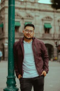 Home Casual portrait of a man leaning on a pole in an urban environment, featuring classic architecture.