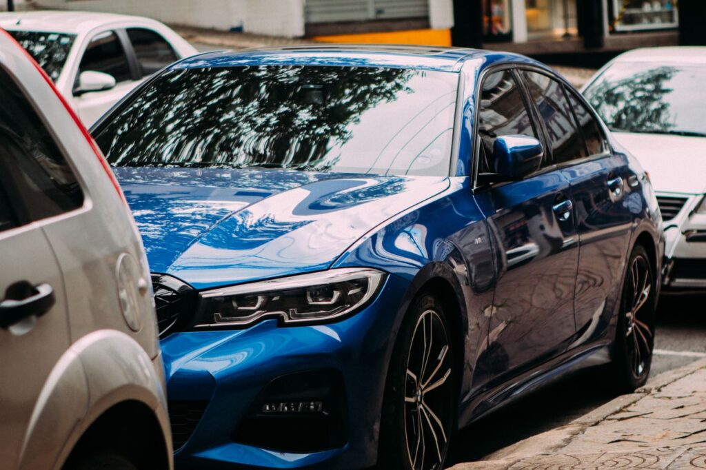 pexels photo 34965678 A vibrant blue luxury sedan parked on an urban street among cars.