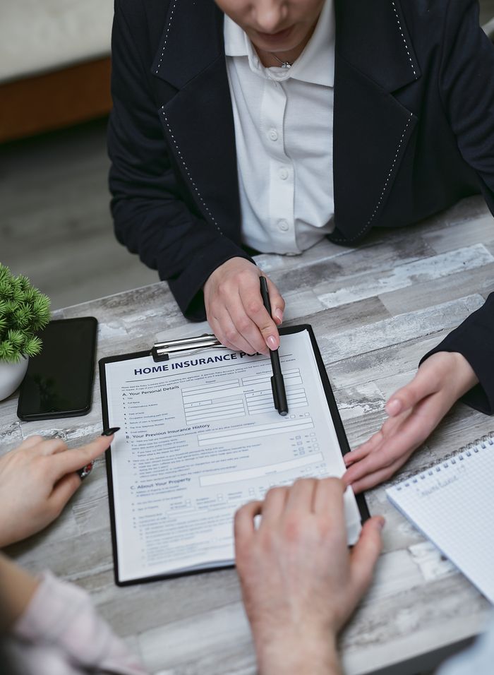 Mastering the First Impression: Your intriguing post title goes here An agent and clients discussing paperwork for home insurance at a meeting table.