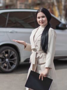 Businesswoman confidently posing on street in white coat, holding a file. Real estate agent concept.